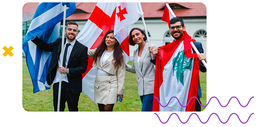 Four smiling young people holding the flags of Greece, Georgia and Lebanon outdoors.