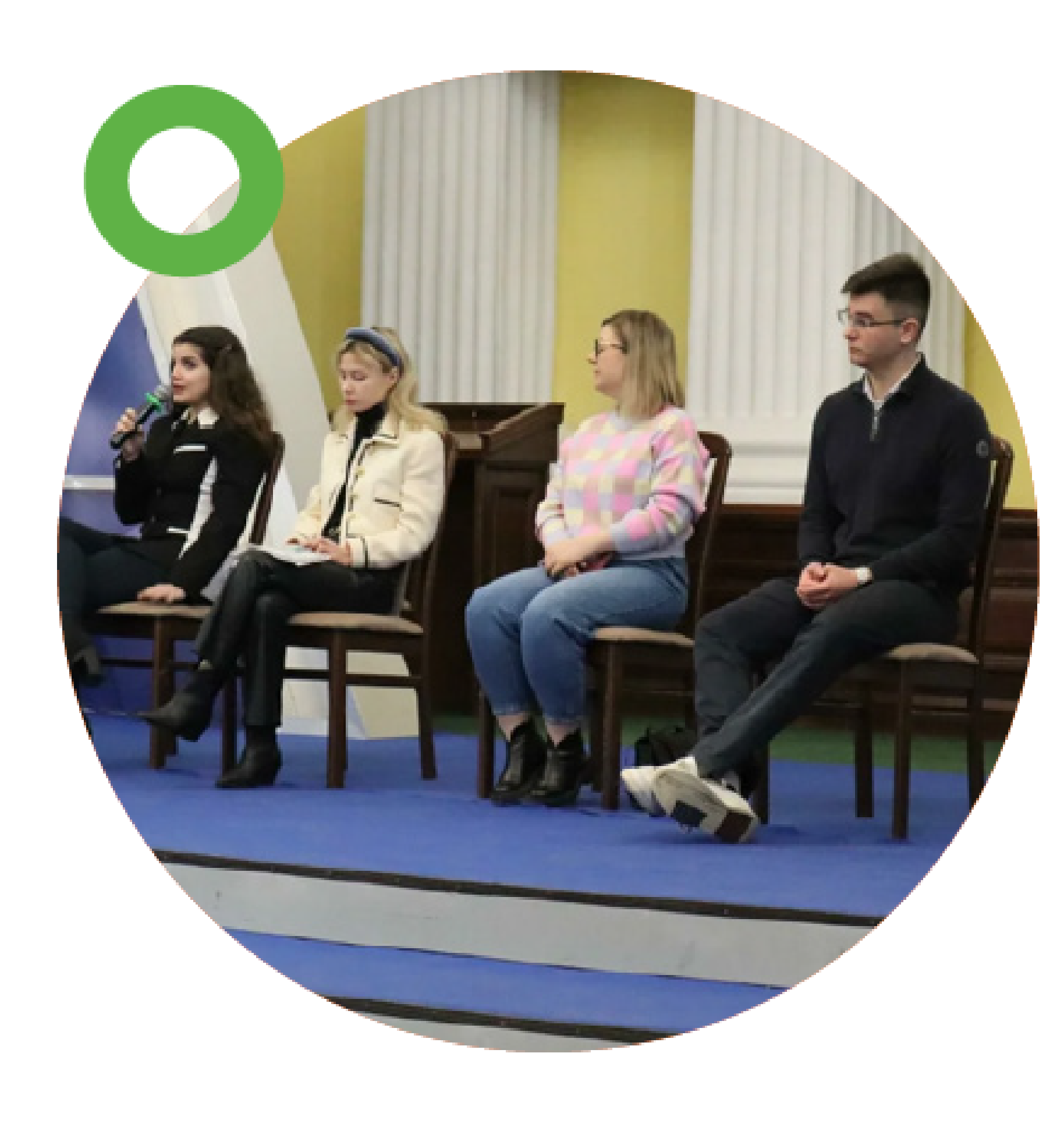 Four young people sitting on chairs during a panel discussion, one of them speaking into a microphone.