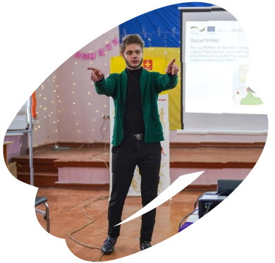 Young facilitator leading an interactive EU4Youth training session, speaking to participants in front of a presentation screen.