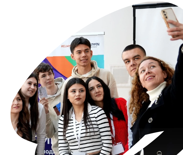 Young participants and facilitator taking a group selfie during an EU4Youth youth engagement or training activity, reflecting teamwork and community spirit.